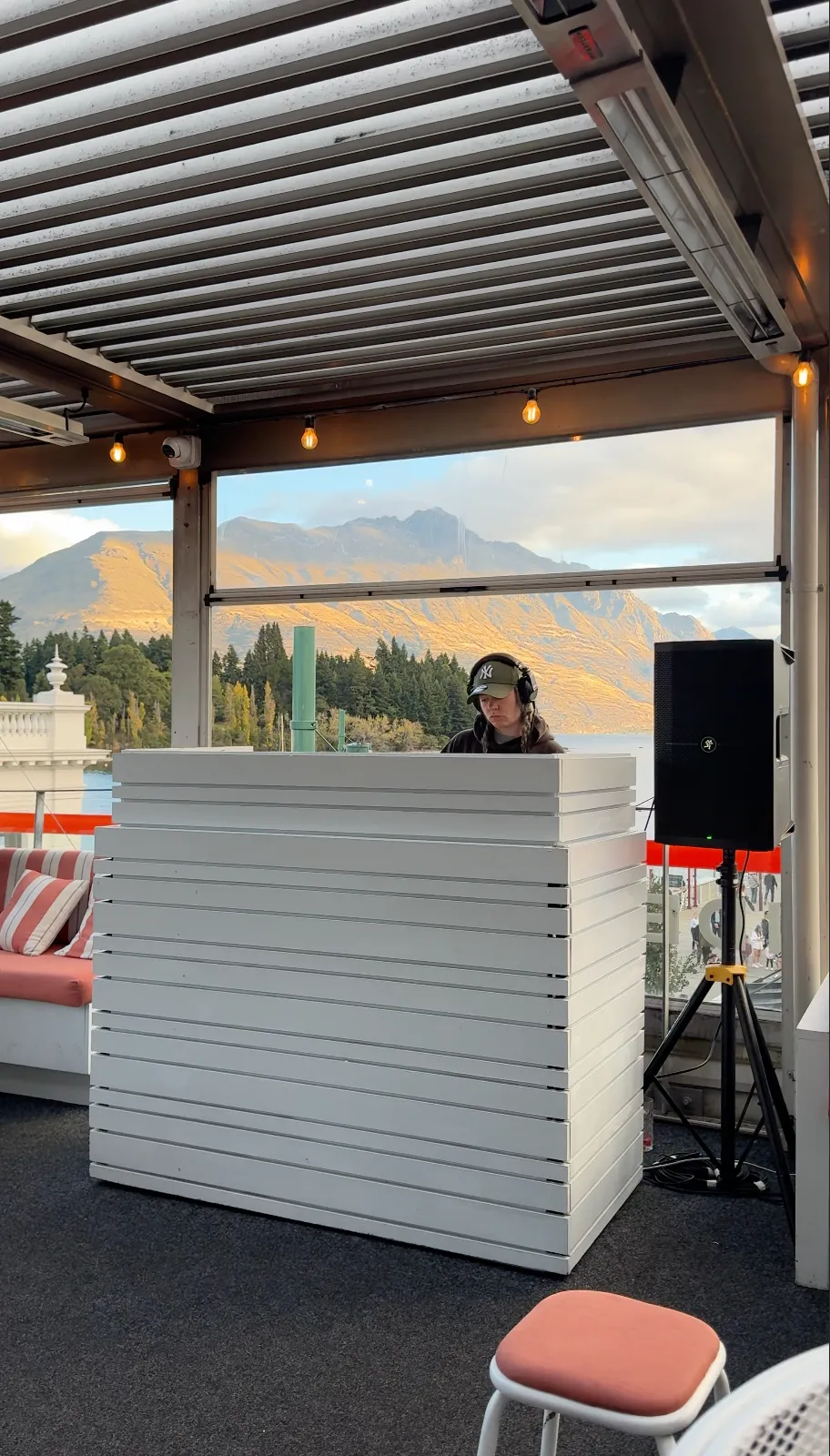 The DJ at The Sundeck, with Queenstown’s mountain scenery behind the rooftop bar.