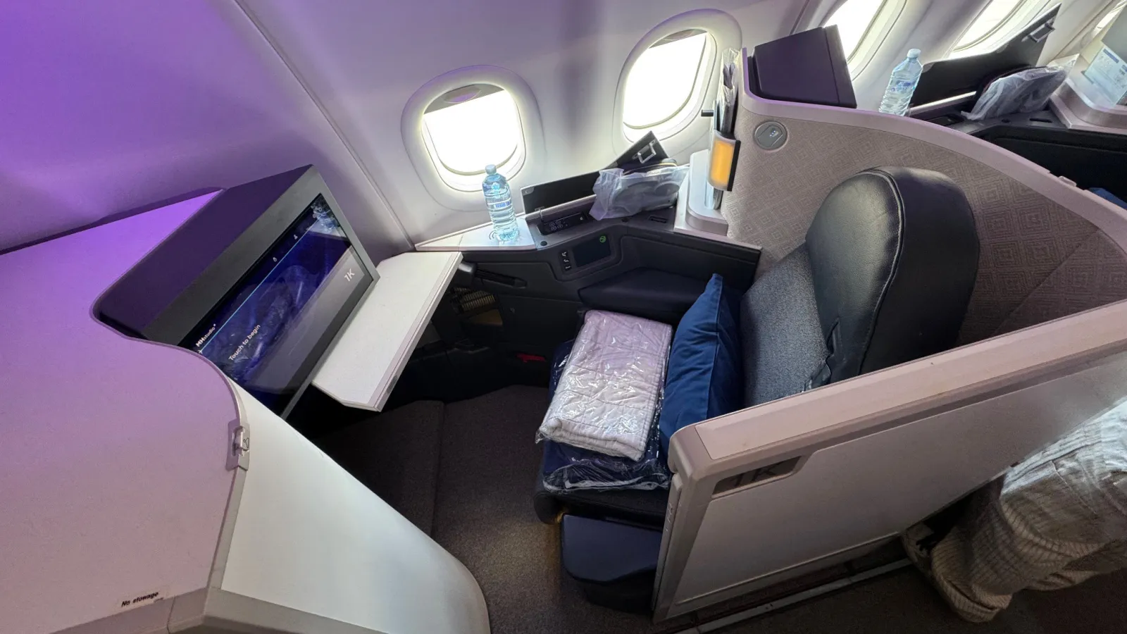 My suite in 1K: navy seat, bedding and the window-side console.